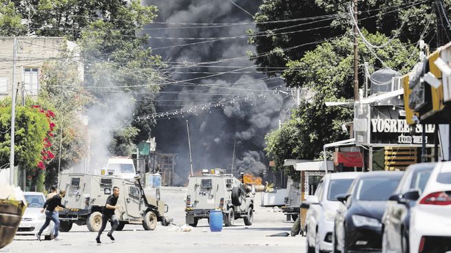 IRRUPCIÓN. Un grupo de palestinos busca refugio en medio de un operativo militar israelí en la ciudad de Yenín.