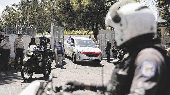 ALERTA. Oficiales de Policía hacen guardia frente al servicio forense de Ecuador, mientras un automóvil transporta el cuerpo del otrora candidato presidencial Fernando Villavicencio.