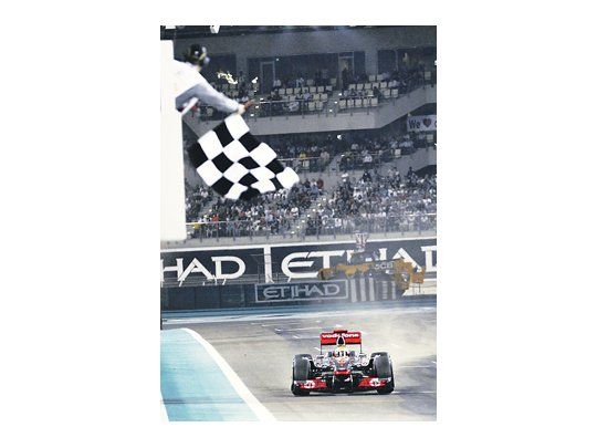 El McLaren del inglés Lewis Hamilton recibe la bandera a cuadros que lo consagra ganador del GP de Abu Dabi.