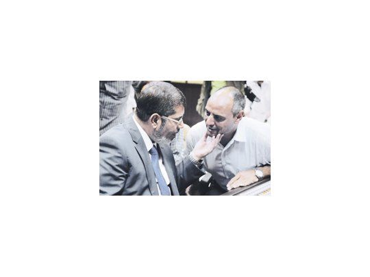 Mohamed Mursi dialoga el domingo con un directivo de la televisión oficial, poco antes de su primera declaración como presidente electo.