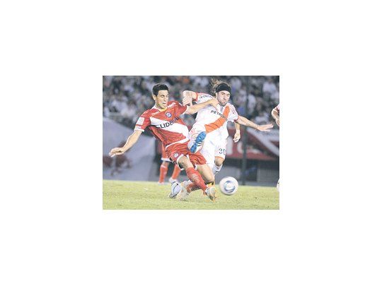 Mariano Pavone lucha con Juan Sabia. A River le faltó osadía y Argentinos se conformó con el empate. Hubo mucha lucha y poco fútbol.