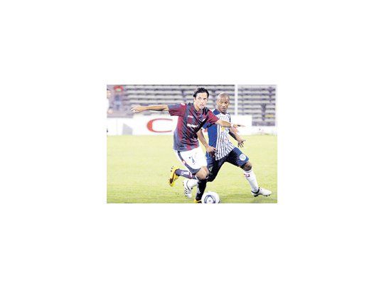 Juan Carlos Menseguez supera a Carlos Sánchez. El ahora volante convirtió el primer gol del partido, el segundo en su cuenta personal, y abrió la posibilidad para un gran triunfo de San Lorenzo.