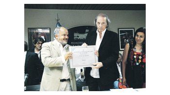 César Luis Menotti recibe del diputado nacional Carlos Comi un diploma en el homenaje que se le realizó al entrenador en la Cámara baja.