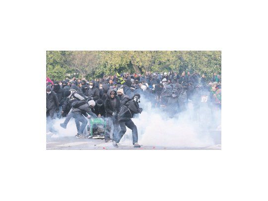 Un grupo de manifestantes arroja latas de humo a la Policía poco después que una marcha pacífica recorriera las principales calles de de París.