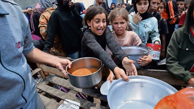 Niños piden comida en un punto de distribución de ayuda humanitaria en el centro de Gaza.