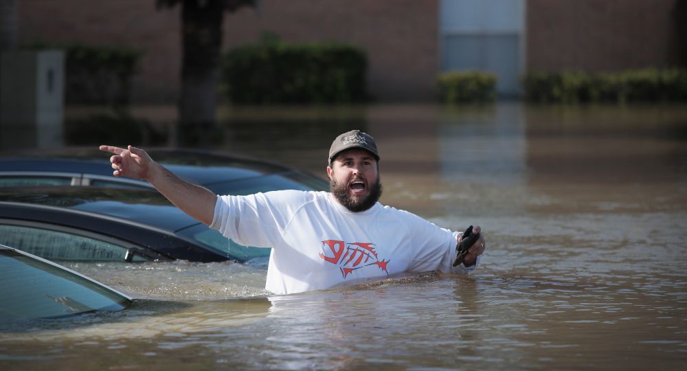 Un hombre le señala un grupo de personas a un bote de rescate para que pueda acudir en su ayuda.