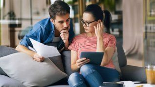 Una pareja analiza sus finanzas con incertidumbre ante el impacto del aumento del dólar en sus planes de adquirir una vivienda