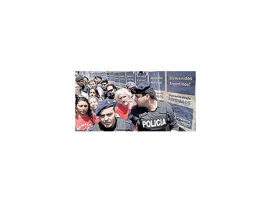 Policías uruguayos custodian a los asambleístas argentinos que viajaron a Montevideo para protestar contra Botnia. Atrás, afiches de la campaña oficial para atraer turistas.
