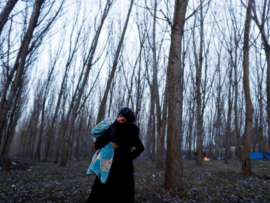 Una mujer deambula con su hijo en brazos en la frontera entre Turquía y Grecia.