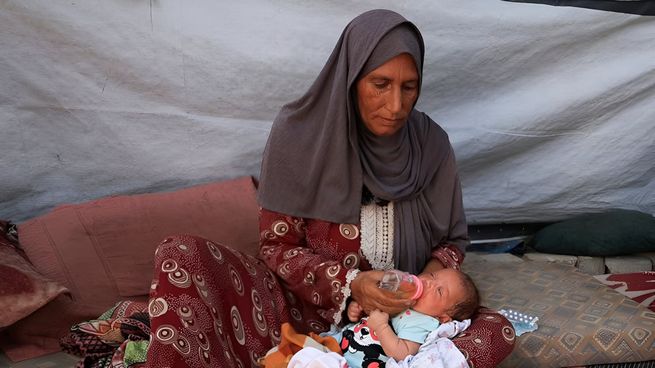 Una abuela alimenta a su nieta con agua colada de sopa en una tienda improvisada de Gaza. No hay leche ni fórmula, solo desesperación.