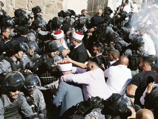 Cuerpo a cuerpo. Policías israelíes y fieles musulmanes forcejean en medio de generalizados disturbios en Jerusalén. Se teme una escalada de la violencia religiosa.