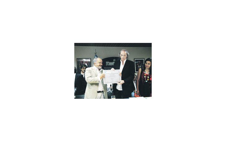 César Luis Menotti recibe del diputado nacional Carlos Comi un diploma en el homenaje que se le realizó al entrenador en la Cámara baja.