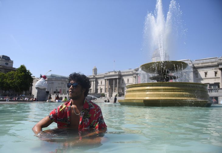 Un hombre se refresca en una fuente de Londres.