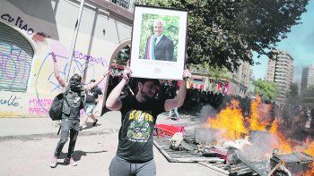 Incendio. Un manifestante muestra un retrato del presidente Sebasti&aacute;n Pi&ntilde;era frente a una barricada. Anoche, al inicio del estado de excepci&oacute;n, se reportaban nuevos incidentes.&nbsp;