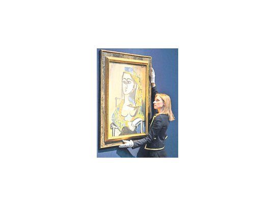 Una empleada de Christie´s exhibe “Femme au costume turc dans un fauteuil” (Mujer con traje turco en un sillón), de Picasso.