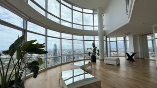 Living de grandes dimensiones en Puerto Madero con doble altura y ventanales curvos que ofrecen vistas panorámicas de la Ciudad y el río Living de grandes dimensiones en Puerto Madero con doble altura y ventanales curvos que ofrecen vistas panorámicas de la Ciudad y el río