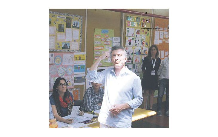 Mauricio Macri saluda al balcón del primer piso del colegio donde votó ayer. Desde allí lo saludaron fiscales y votantes.
