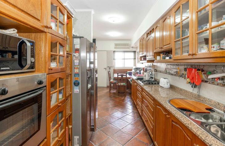 La cocina conserva dimensiones poco frecuentes en los proyectos actuales. Mobiliario de madera, amplias superficies de trabajo y espacio para comedor diario forman parte de una distribución pensada para la vida cotidiana La cocina conserva dimensiones poco frecuentes en los proyectos actuales. Mobiliario de madera, amplias superficies de trabajo y espacio para comedor diario forman parte de una distribución pensada para la vida cotidiana