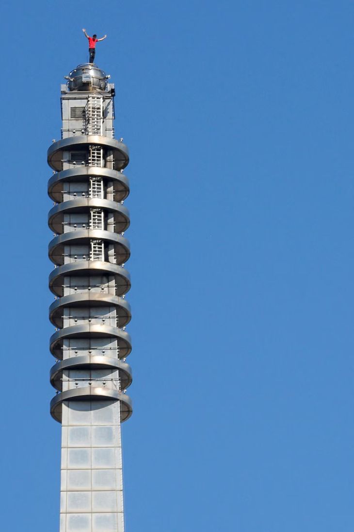 El escalador se mantuvo de pie sobre la aguja del rascacielos sin protección alguna. El escalador se mantuvo de pie sobre la aguja del rascacielos sin protección alguna.