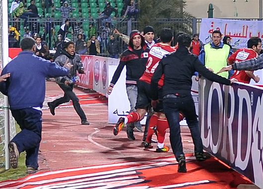 Los jugadores de Al-Ahly intentan escapar del caos en la cancha.