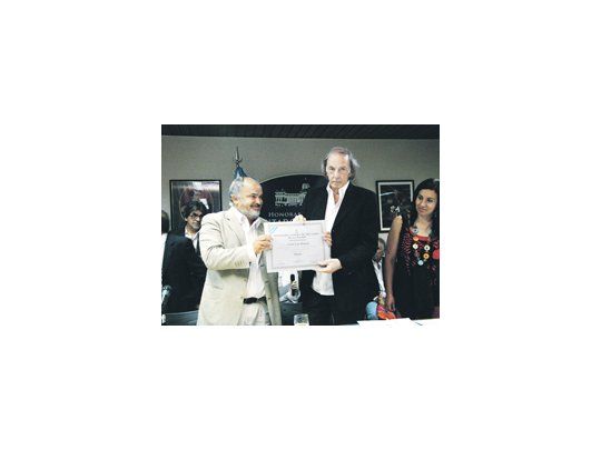 César Luis Menotti recibe del diputado nacional Carlos Comi un diploma en el homenaje que se le realizó al entrenador en la Cámara baja.