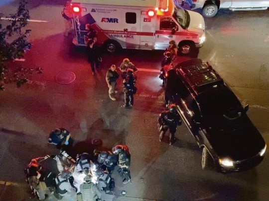 DESCONTROL. Médicos y policías asistieron en plena calle a una víctima de disparos en Portland, estado de Oregon, en la noche del sábado.