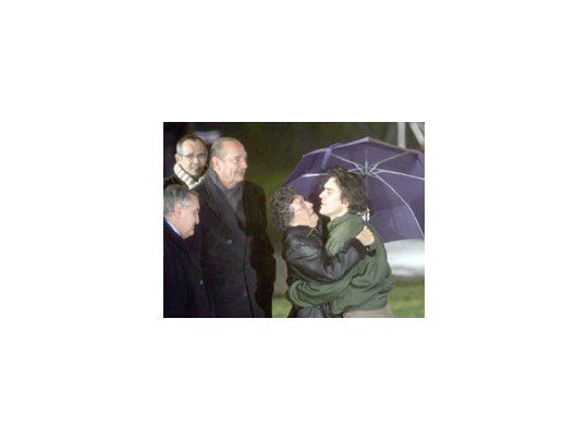 El ex rehén Georges Malbrunot abraza a su madre al pisar suelo francés, ante la vista del presidente Jacques Chirac y del premier Jean-Pierre Raffarin. El gobierno negó haber pagado rescate por los dos rehenes.