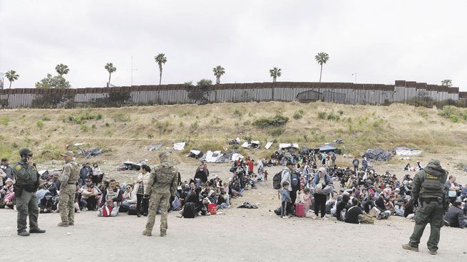 TENSA ESPERA. Centenares de personas que aspiran a ingresar a California aguardaban ayer, custodiadas, en medio de un complejo de cercas apostadas en el límite con México.