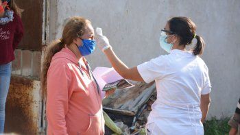 Una trabajadora municipal realizando un control de temperatura a una vecina del barrio popular José Luis Cabezas.