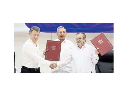 HISTÓRICO. El presidente de Colombia, Juan Manuel Santos, y el líder de las FARC, Rodrigo Londoño, se estrechan la mano y muestran el acuerdo de cese del fuego definitivo. Raúl Castro fue el garante de las negociaciones.