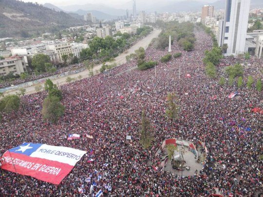 En la bandera puede leerse la frase No estamos en guerra con la que el pueblo le responde a Piñera.&nbsp;
