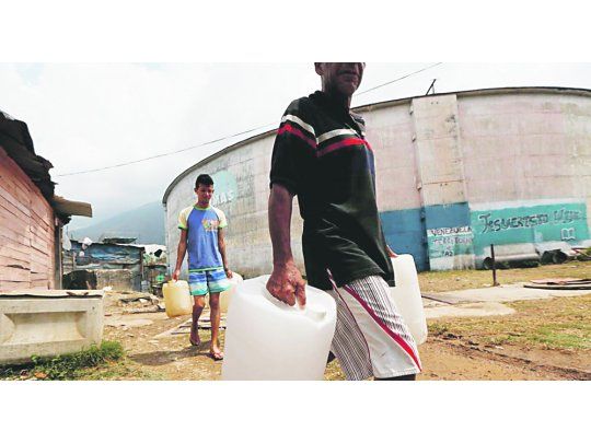 PRECARIEDAD. Dos venezolanos caminan, bidones en mano, para buscar agua para sus hogares en la ciudad de Puerto Ordaz.