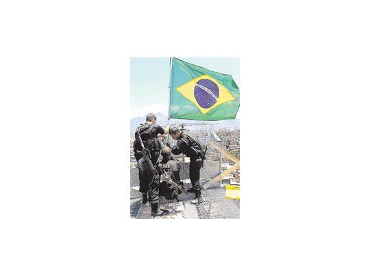Policías brasileños colocaron ayer la bandera nacional en lo alto del Complexo do Alemao, arrebatado a los jefes del narcotráfico que habían predominado allí durante años. La presencia policial y militar en la nueva megafavela «liberada» se prolongará en el tiempo, atendiendo al temor popular de que el espectacular operativo de ayer no impida un retorno de los mafiosos.