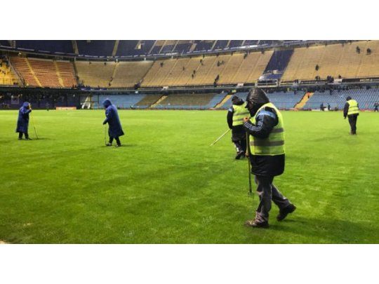 Empleados de Boca Juniors reacondicionan el césped donde jugarán Argentina y Perú por las Eliminatorias sudamericanas.