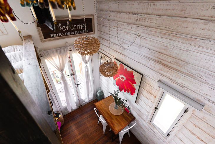 Desde el nivel superior se observa el comedor con mesa de madera maciza y sillas metálicas. Las luminarias de fibras naturales aportan calidez. El revestimiento interior está realizado en tablas pintadas a la cal, con aberturas de aluminio y detalles decorativos que refuerzan el estilo rústico Desde el nivel superior se observa el comedor con mesa de madera maciza y sillas metálicas. Las luminarias de fibras naturales aportan calidez. El revestimiento interior está realizado en tablas pintadas a la cal, con aberturas de aluminio y detalles decorativos que refuerzan el estilo rústico