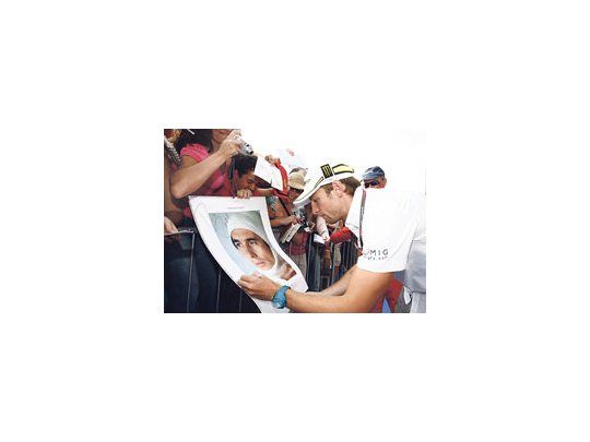 El británico Jenson Button firma autógrafos sobre un póster de Ayrton Senna.