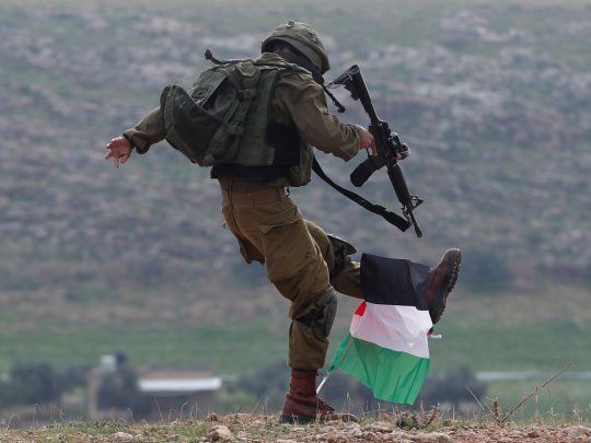 Un soldado israelí patea una bandera palestina durante una manifestación en Cisjordania.