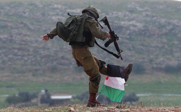 An Israeli soldier kicks a Palestinian flag during a demonstration in the West Bank.