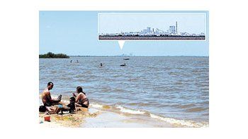 Tras la denuncia de fuertes olores en la zona, una familia se baña en las costas del río Uruguay. Alfondo se puede ver la pastera Botnia.