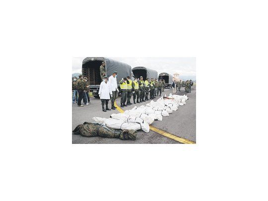 Policías y soldados colombianos custodian los cuerpos de los rebeldes de las FARC abatidos en un operativo sobre la frontera con Ecuador. Un niño apareció entre las víctimas.