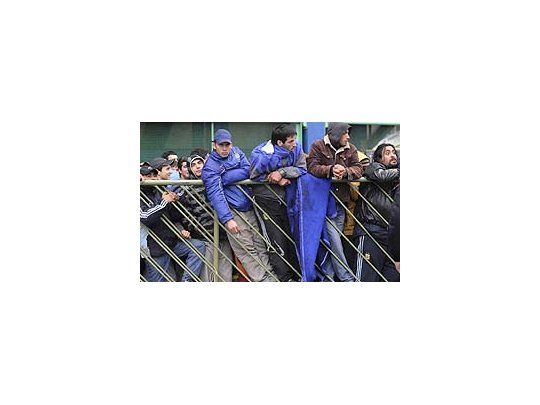 La gente hace cola detrás de las vallas ante la atenta mirada policial.