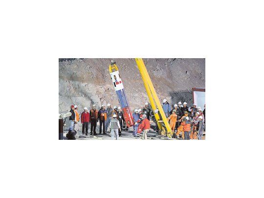 La televisión mundial siguió paso a paso los preparativos de la cápsula antes del inicio de la operación de rescate de los mineros (izquierda). Los retratos de los trabajadores anticipaban en el campamento el esperado reencuentro con sus seres queridos (derecha).
