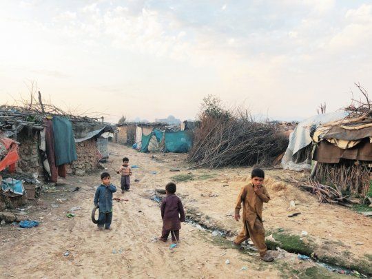 DESAMPARO. Un grupo de ni&ntilde;os afganos camina por un campo de refugiados en Islamabad, Pakist&aacute;n. Afganist&aacute;n est&aacute; sumida en la violencia desde hace d&eacute;cadas.