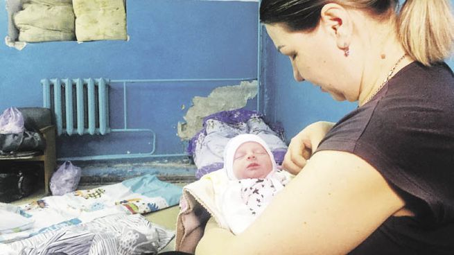 TERROR. Una mujer cuida de su hijo recién nacido en un refugio en Járkov, la segunda ciudad de Ucrania, donde los combates han recrudecido. Un grupo de familiares traslada los ataúdes de los profesores Yelena Ivanova and Yelena Kudrik, que murieron durante bombardeos en Donetsk.