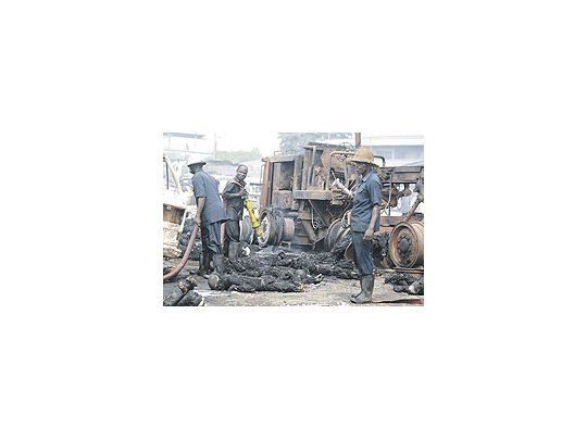 Un grupo de bomberos nigerianos culmina la tarea de apagar el incendio desatado en unoleoducto de Lagos, en medio de los cuerpos carbonizados. El robo de combustibles a travésde la rotura de ductos frecuentemente deriva en tragedias.