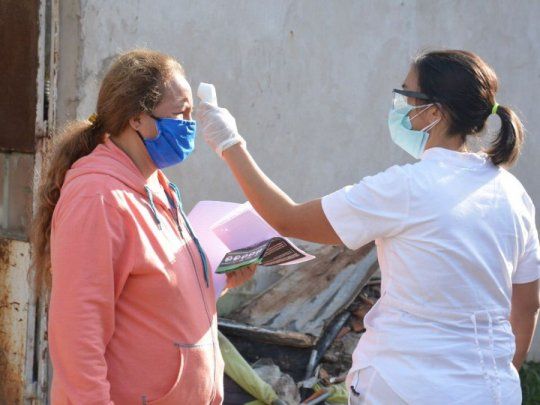 Una trabajadora municipal realizando un control de temperatura a una vecina del barrio popular José Luis Cabezas.