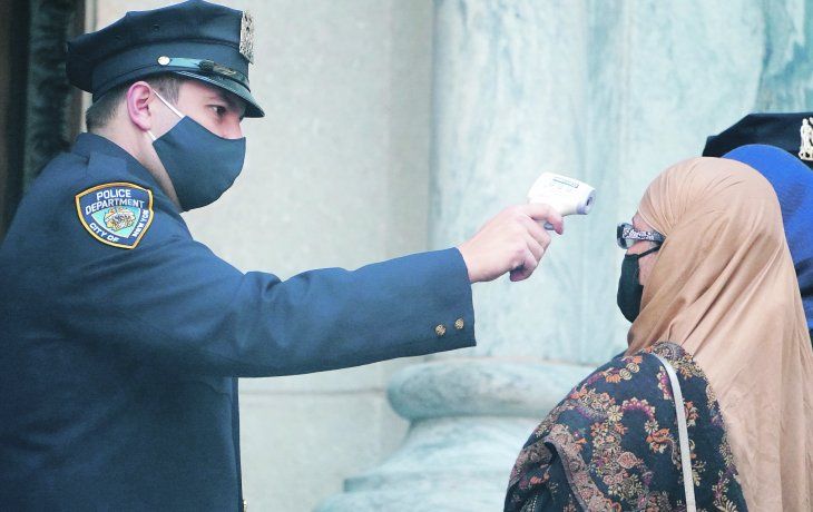 PREVENCIONES. Un policía de Nueva York controla la temperatura de los fieles que ingresan a la Catedral de St. Patrick, donde se desarrolló una misa por los 46 miembros de la fuerza que han muerto de covid-19.
