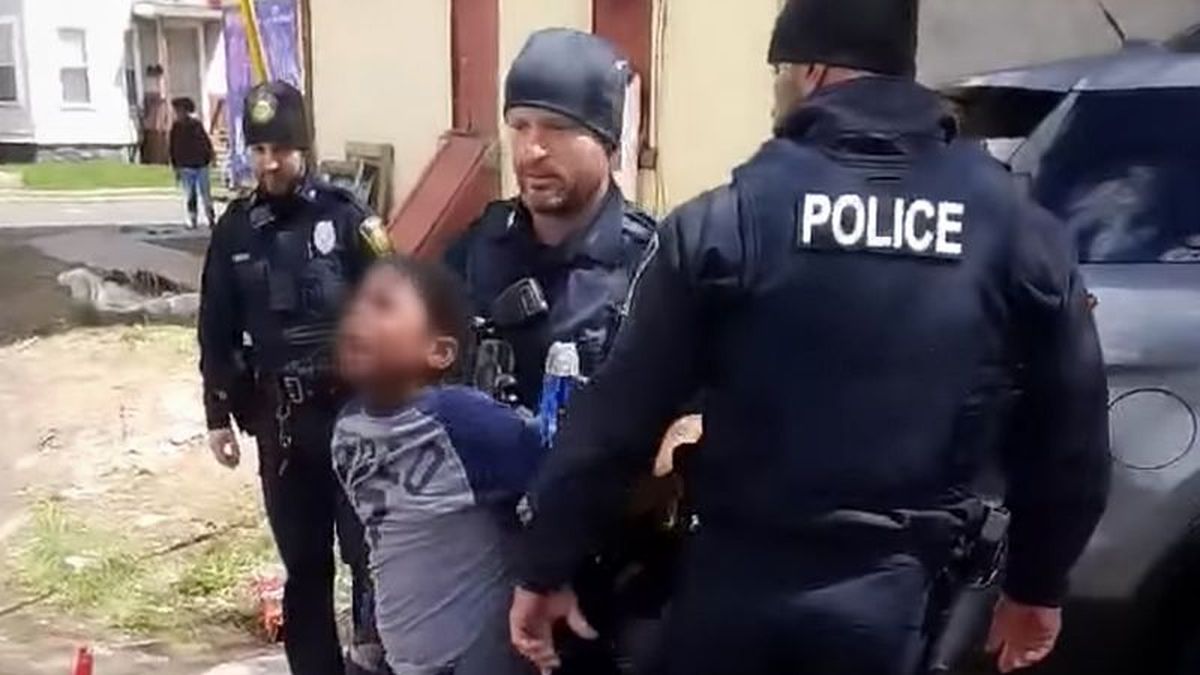 US police officers arrest a boy for stealing a packet of potato chips