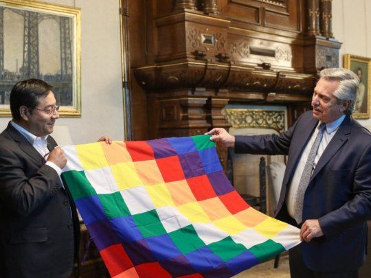 Luis Arce y Alberto Fernández sosteniendo una whipala, símbolo de los pueblos originarios de Bolivia.