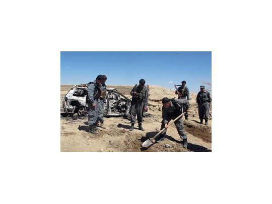 Policías afganos buscan restos al lado de un auto destruido por un ataque de helicóptero de la OTAN, donde denuncian que mataron a dos niños.